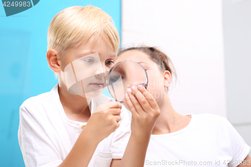 Image of Steatite, mineral. Geography at school. Mineral. Two children, a girl and a boy watching through a magnifying glass stones from his collection of rocks.