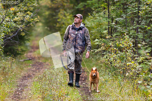 Image of hunter with dog walking on the road