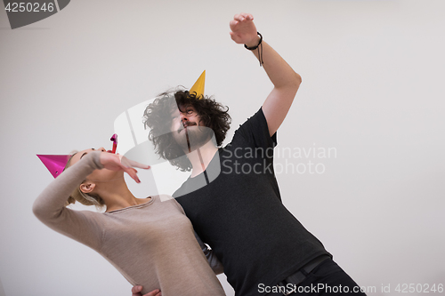 Image of couple in party hats blowing in whistle