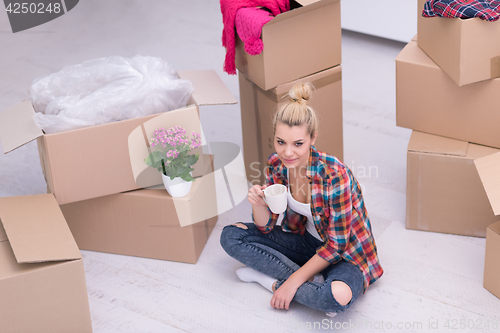 Image of woman with many cardboard boxes sitting on floor