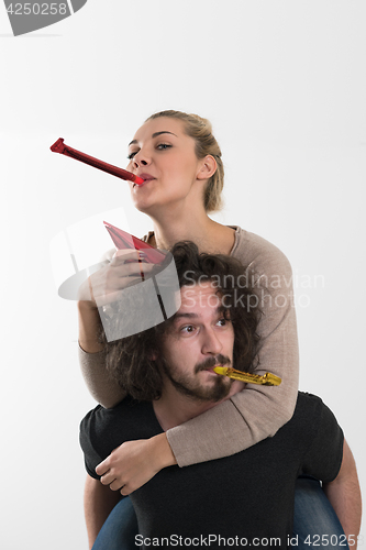 Image of couple in party hats blowing in whistle