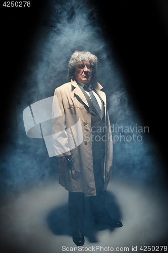 Image of Senior police agent with a gun on dark smoke background