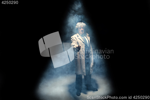 Image of Senior police agent with a gun on dark smoke background