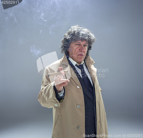 Image of The senior man with cigar as detective or boss of mafia on gray studio background