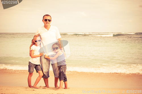 Image of Father and children playing on the beach at the day time.