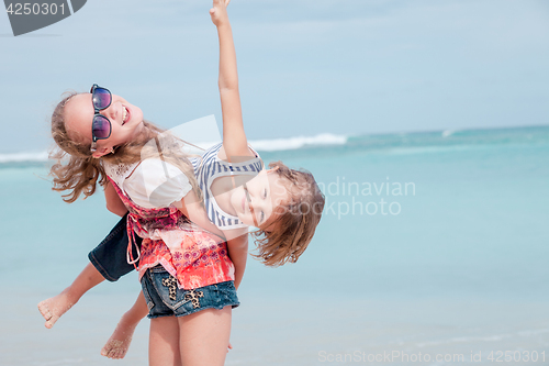 Image of Sister and brother playing on the beach at the day time.