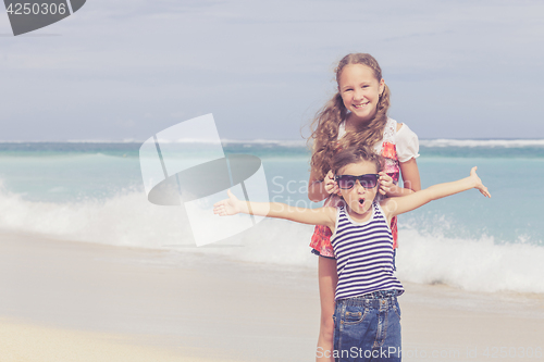 Image of Sister and brother playing on the beach at the day time.