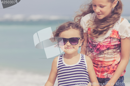 Image of Sister and brother playing on the beach at the day time.