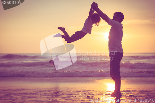 Image of Father and son playing on the beach at the sunset time.