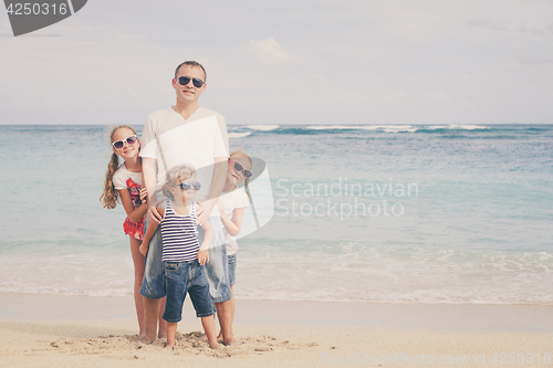 Image of Father and children playing on the beach at the day time.