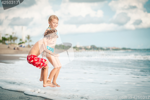 Image of Sister and brother playing on the beach at the day time.