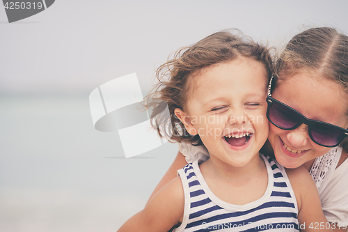 Image of Sister and brother playing on the beach at the day time.