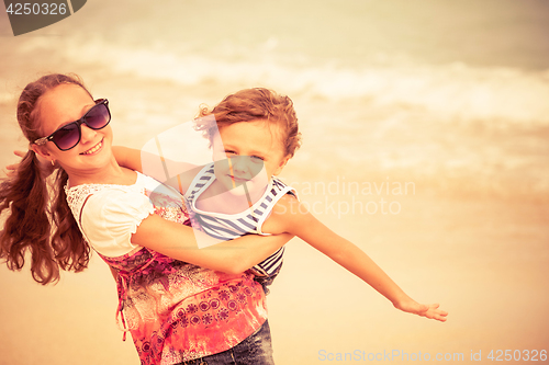 Image of Sister and brother playing on the beach at the day time.
