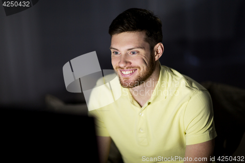 Image of happy smiling young man watching tv at night
