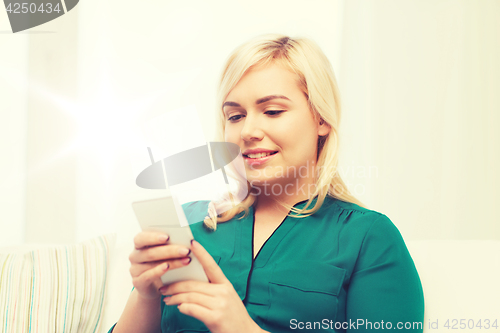 Image of happy woman with smartphone at home