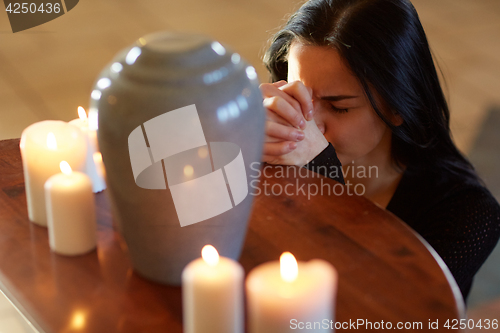 Image of sad woman with funerary urn praying at church