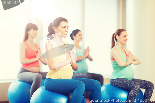 Image of happy pregnant women exercising on fitball in gym