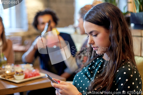 Image of woman with smartphone and friends at restaurant