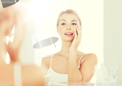 Image of happy young woman looking to mirror at bathroom