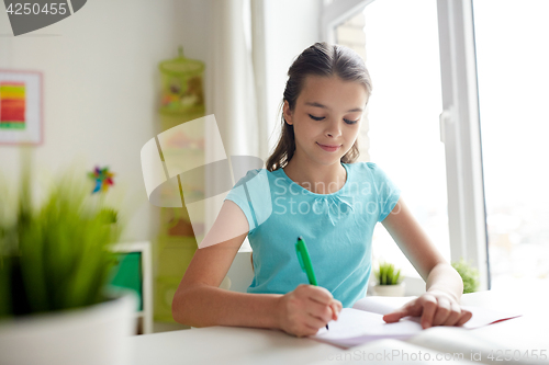 Image of happy girl writing to notebook at home