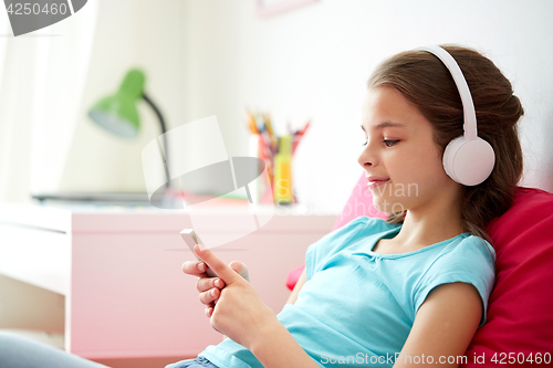 Image of happy girl with smartphone and headphones at home