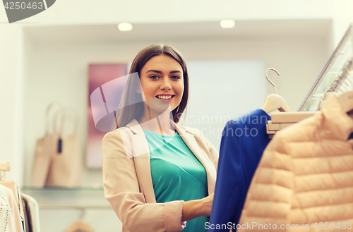 Image of happy young woman choosing clothes in mall