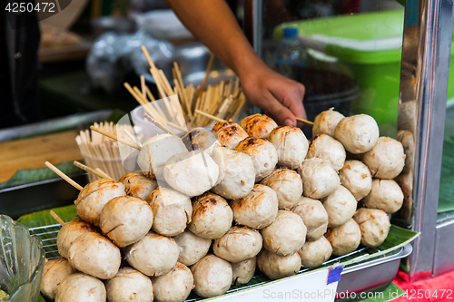 Image of seller hand with meatballs at street market