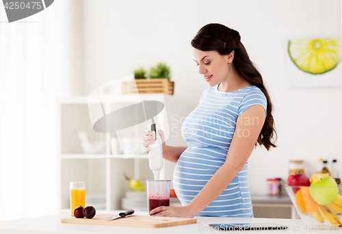 Image of pregnant woman with blender cooking fruits at home