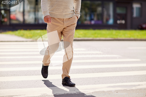 Image of senior man walking along city crosswalk