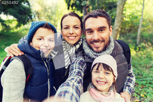 Image of family with backpacks taking selfie and hiking