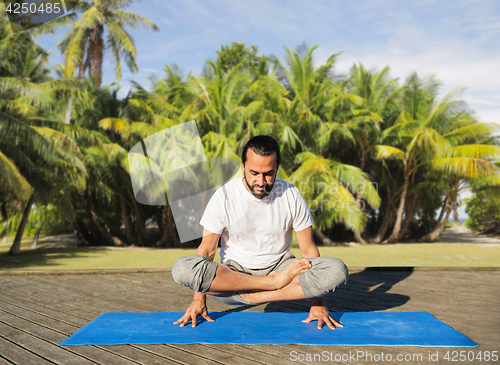 Image of man making yoga in scale pose outdoors