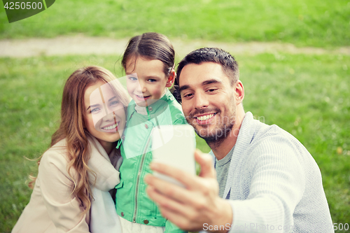 Image of happy family taking selfie by smartphone outdoors