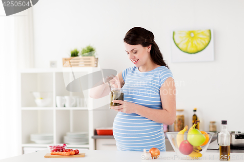 Image of pregnant woman eating pickles at home kitchen