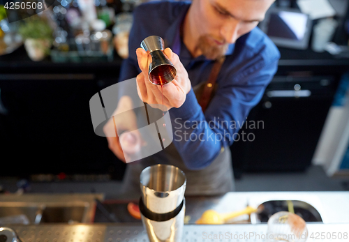 Image of bartender with shaker preparing cocktail at bar