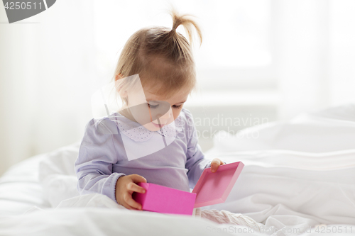 Image of happy little baby girl with gift box at home