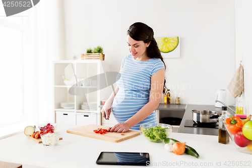 Image of pregnant woman cooking vegetables at home