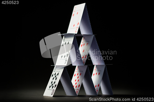 Image of house of playing cards over black background