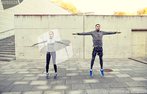 Image of happy man and woman jumping outdoors