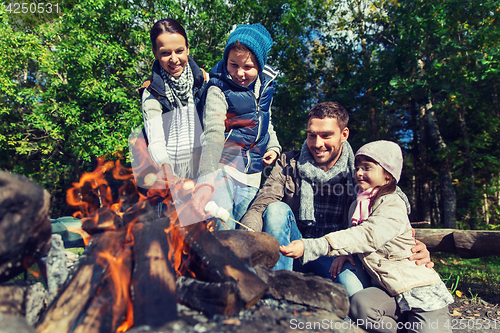 Image of happy family roasting marshmallow over campfire