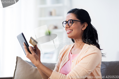 Image of happy woman with tablet pc and credit card at home