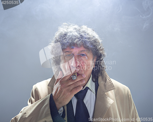 Image of The senior man with cigar as detective or boss of mafia on gray studio background