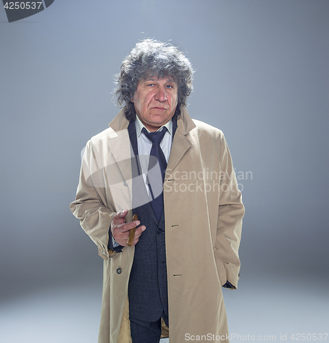 Image of The senior man with cigar as detective or boss of mafia on gray studio background