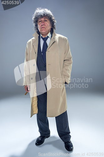 Image of The senior man with cigar as detective or boss of mafia on gray studio background