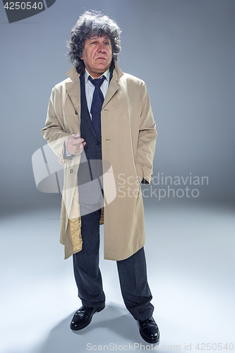 Image of The senior man with cigar as detective or boss of mafia on gray studio background