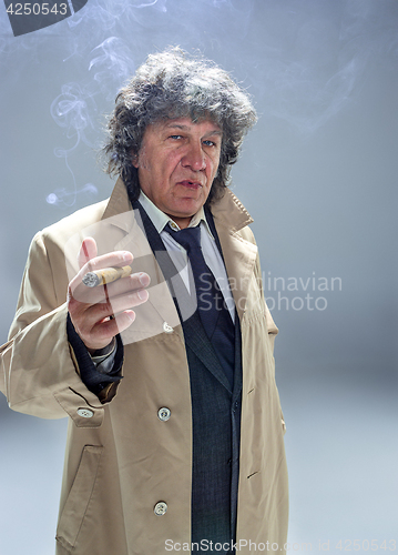 Image of The senior man with cigar as detective or boss of mafia on gray studio background