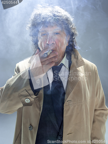 Image of The senior man with cigar as detective or boss of mafia on gray studio background