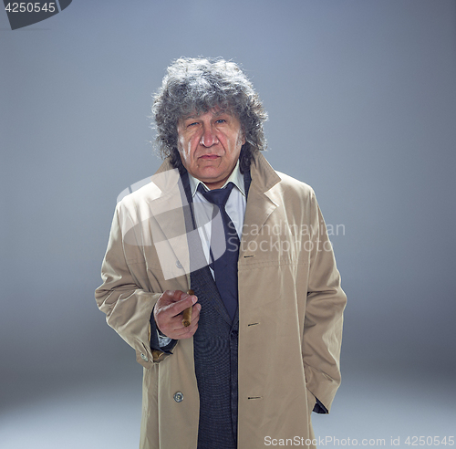 Image of The senior man with cigar as detective or boss of mafia on gray studio background