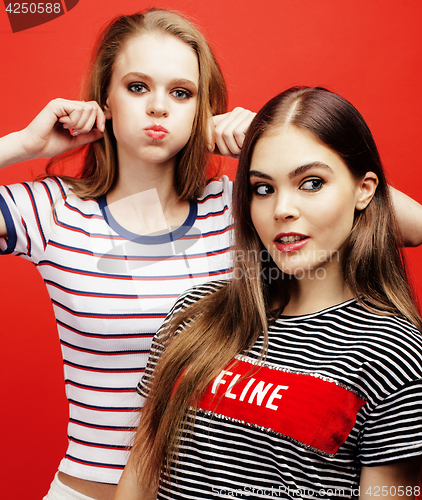 Image of two best friends teenage girls together having fun, posing emotional on red background, besties happy smiling, lifestyle people concept close up