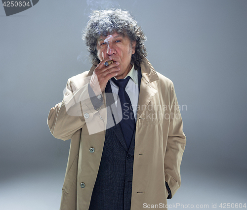 Image of The senior man with cigar as detective or boss of mafia on gray studio background