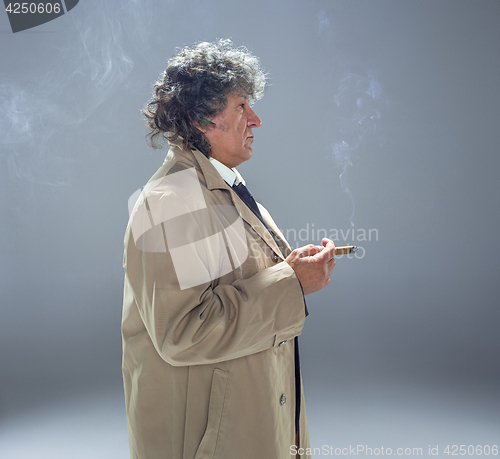 Image of The senior man with cigar as detective or boss of mafia on gray studio background